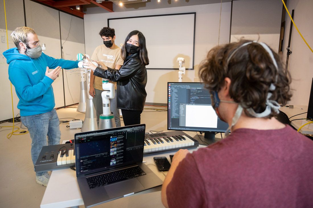 The four Georgia Tech researchers working with one of the robots.